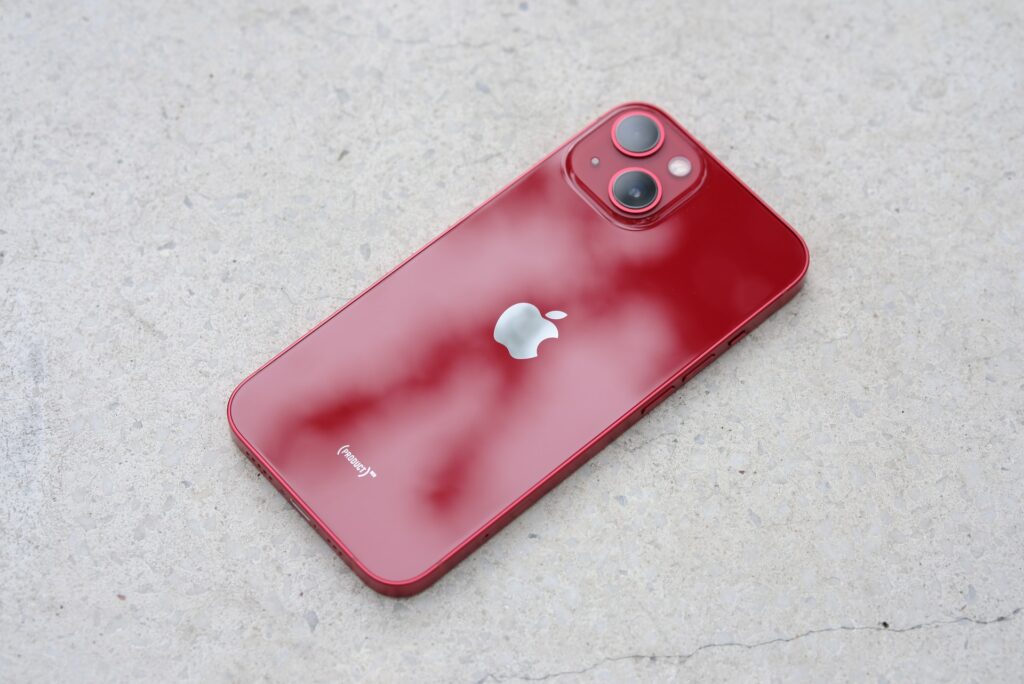 iphone 13 product red posé sur une table de dos avec des reflets de  lumière