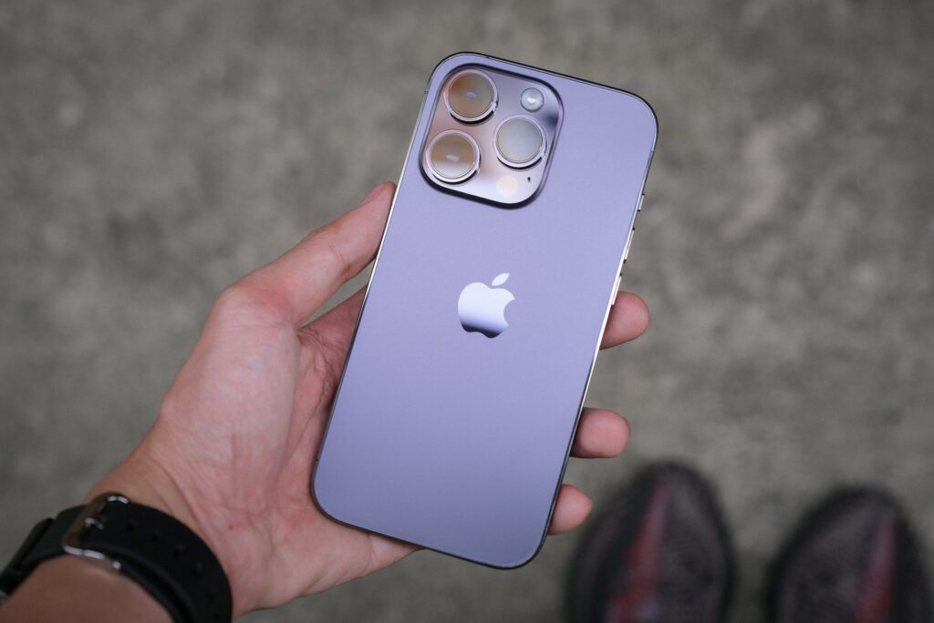 Vue rapprochée du dos de l'iPhone 14 Pro en coloris violet capturant la brillance du verre et le design distinctif du module de caméra