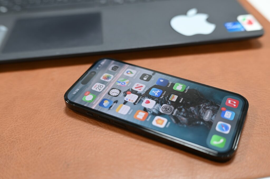 Une image du nouvel iPhone 14 Pro posé sur une table en bois clair et son écran allumé